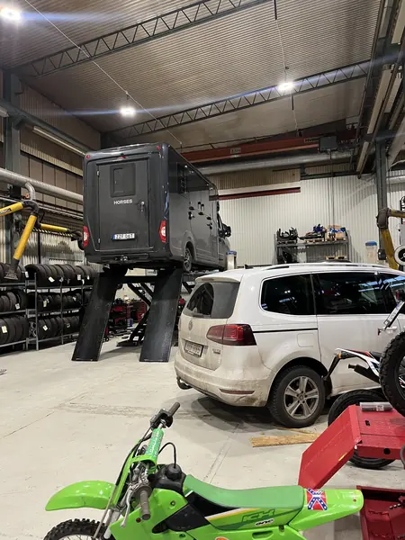 Grön moped bland flera fordon i verkstaden